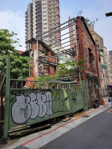 An old brick neighborhood building beside modern high-rises in Taipei