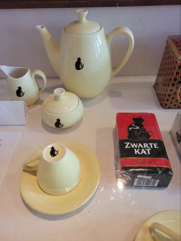 A pale yellow tea set decorated with black cats at the KattenKabinet museum