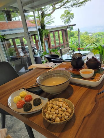 Tea, snacks, and a teapot on a table overlooking the green hills of Maokong