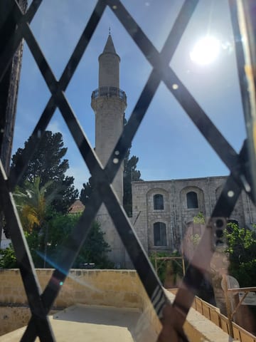 A mosque minaret seen through the iron gate of Larnaca Fort