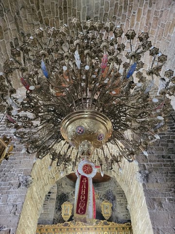 An ornate chandelier hanging beneath the stone arches of the Church of Saint Lazarus