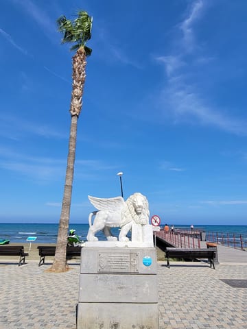 A white lion statue beside Larnaca's palm-lined seaside promenade