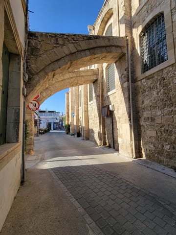 A narrow old-town street passing beneath a weathered stone arch