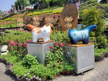Colorful cat sculptures surrounded by flowers at Maokong Station