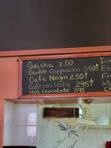 A cafe menu board listing Gesha coffee prices