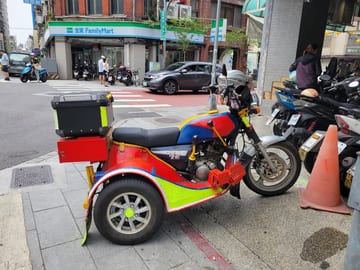 A colorful three-wheeled scooter parked on a Taipei sidewalk
