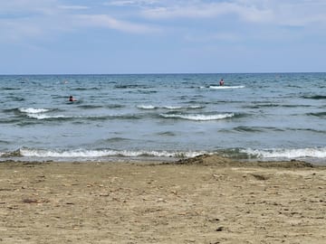 People wading far from shore in Larnaca's shallow blue sea