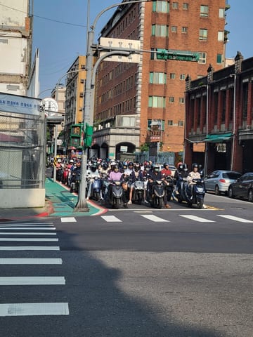 A large group of scooter commuters waiting at a Taipei intersection
