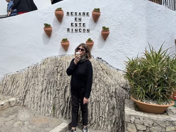 Stacy drinking coffee beneath a Bésame en este rincón sign