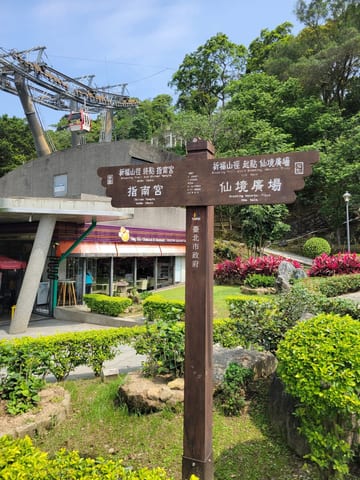 A direction sign with Chinese writing surrounded by gardens near the Zhinan Temple Complex