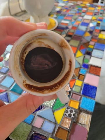 Dark coffee grounds settled at the bottom of a small white cup