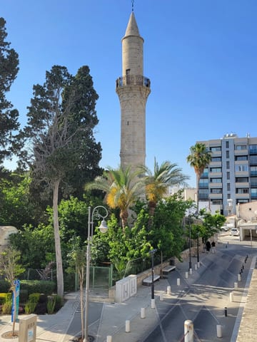 The neighboring mosque's minaret rising above trees and buildings