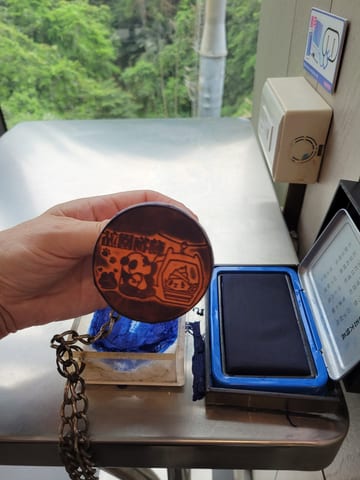 A round souvenir stamp being pressed into a passport-style stamp book