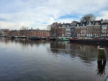 Amsterdam canal lined with tall historic houses on an overcast day