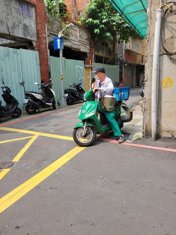 A Taipei mail carrier riding a green motor scooter