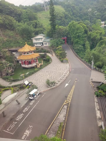 A small pavilion and winding road seen from the gondola above Maokong