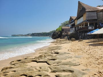 Bingin Beach at low tide with cliffside buildings beside the sand