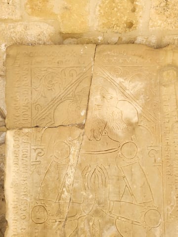 A weathered medieval tombstone carved with a human figure