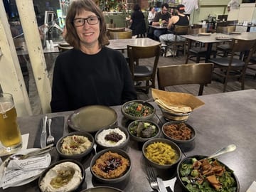 Stacy seated behind a table crowded with the first course of a Cypriot meze dinner