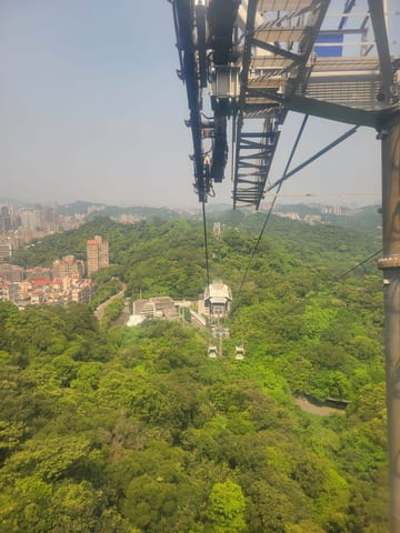 A gondola cabin climbing above green hills toward Maokong