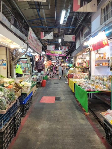 A narrow covered market aisle lined with produce stands