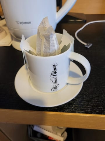 A single-use pour-over coffee filter perched over a hotel room coffee cup