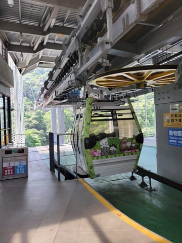 A green Maokong Gondola cabin arriving at the station